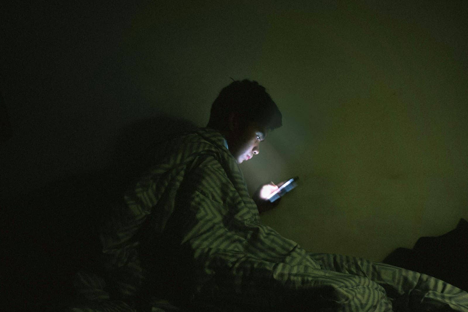 Someone lit by their phone in a dark room